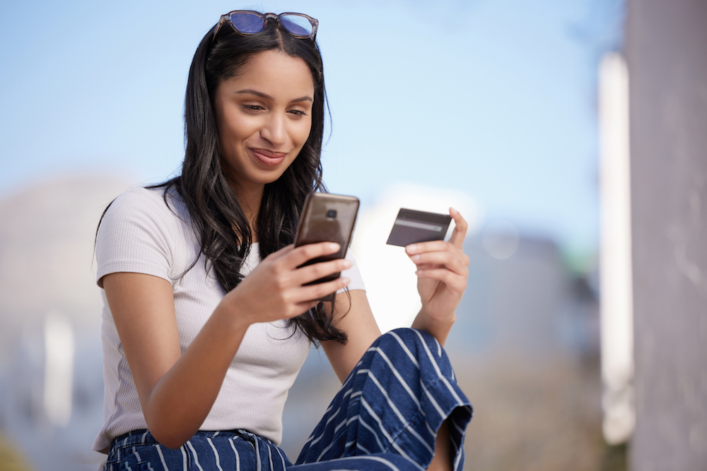 woman on her phone making a purchase with a debit card