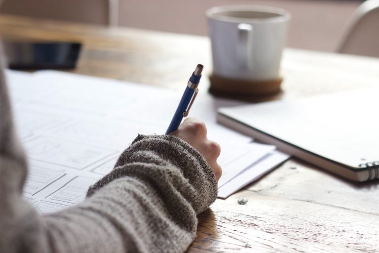 Person writing with a pen to understand the factors that impact their credit score