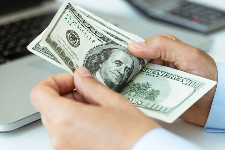 person holding 100 dollar bills in their hands